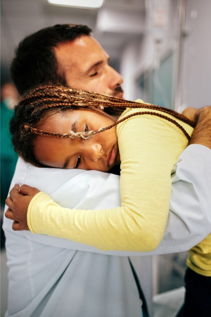 A young doctor comforting a young African American girl